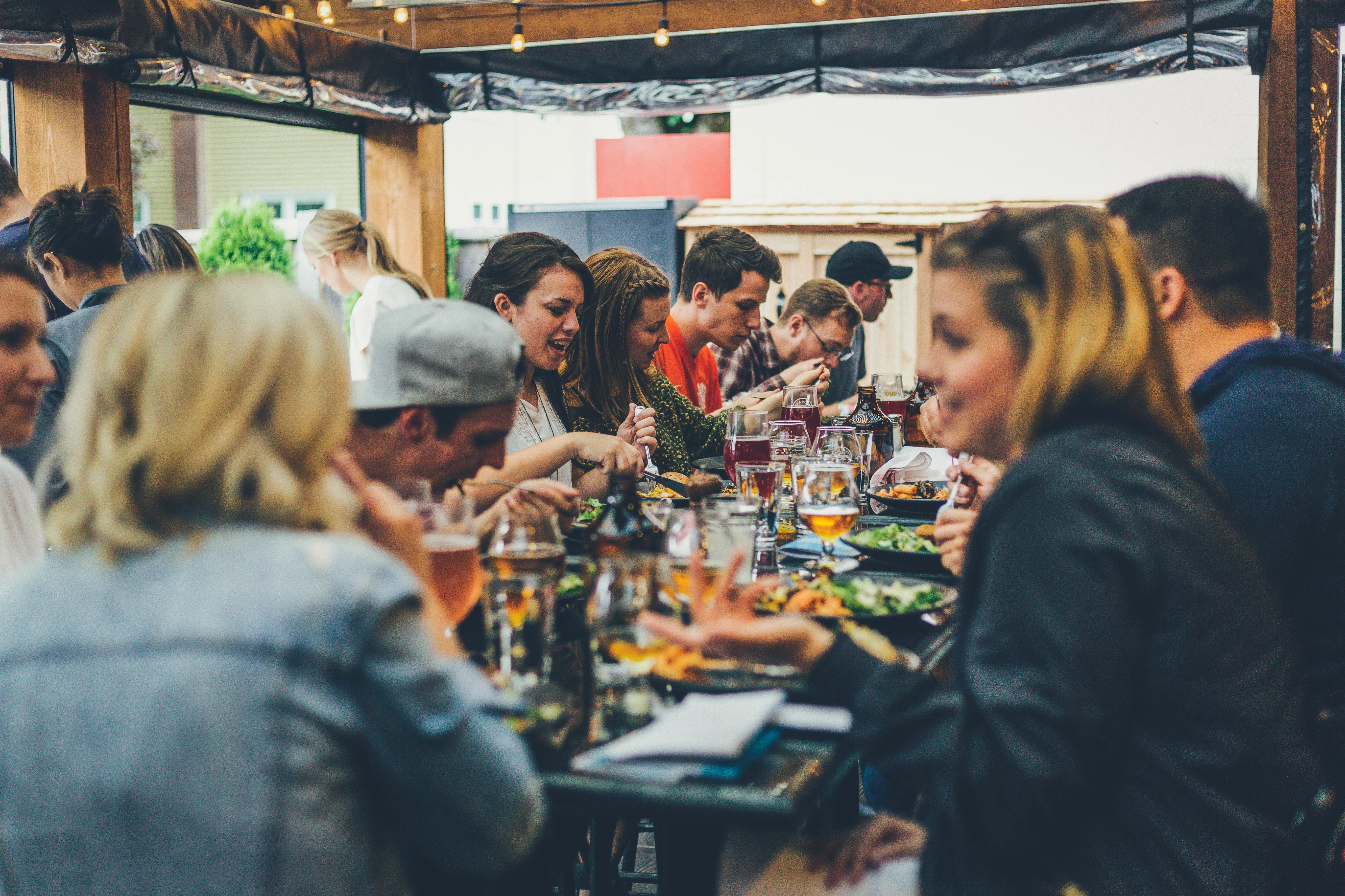 Groep gasten geniet van diner op overdekt terras van restaurant