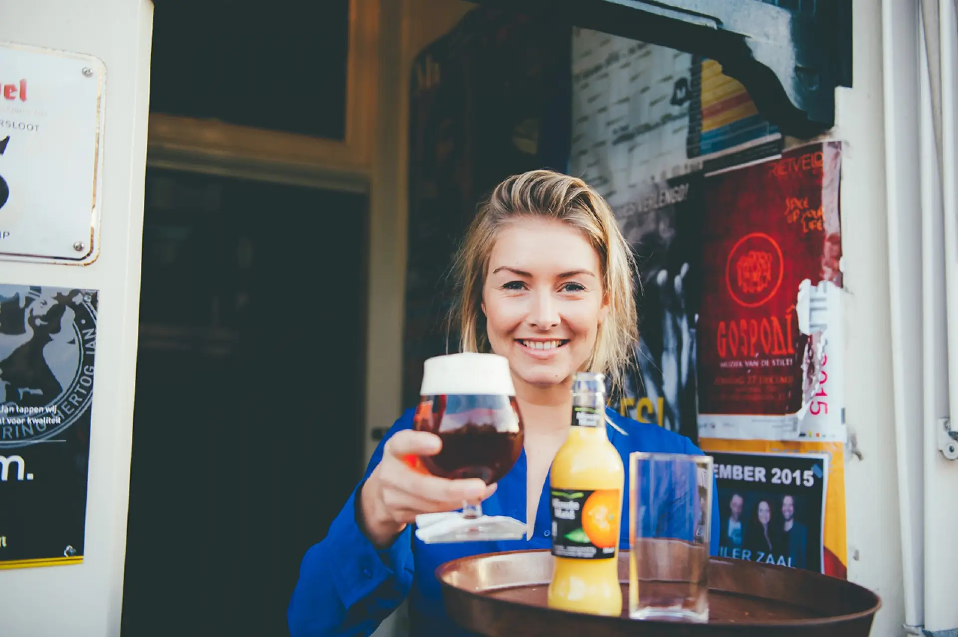 Lachende vrouwelijke ober die een drankje overhandigt vanaf haar dienblad