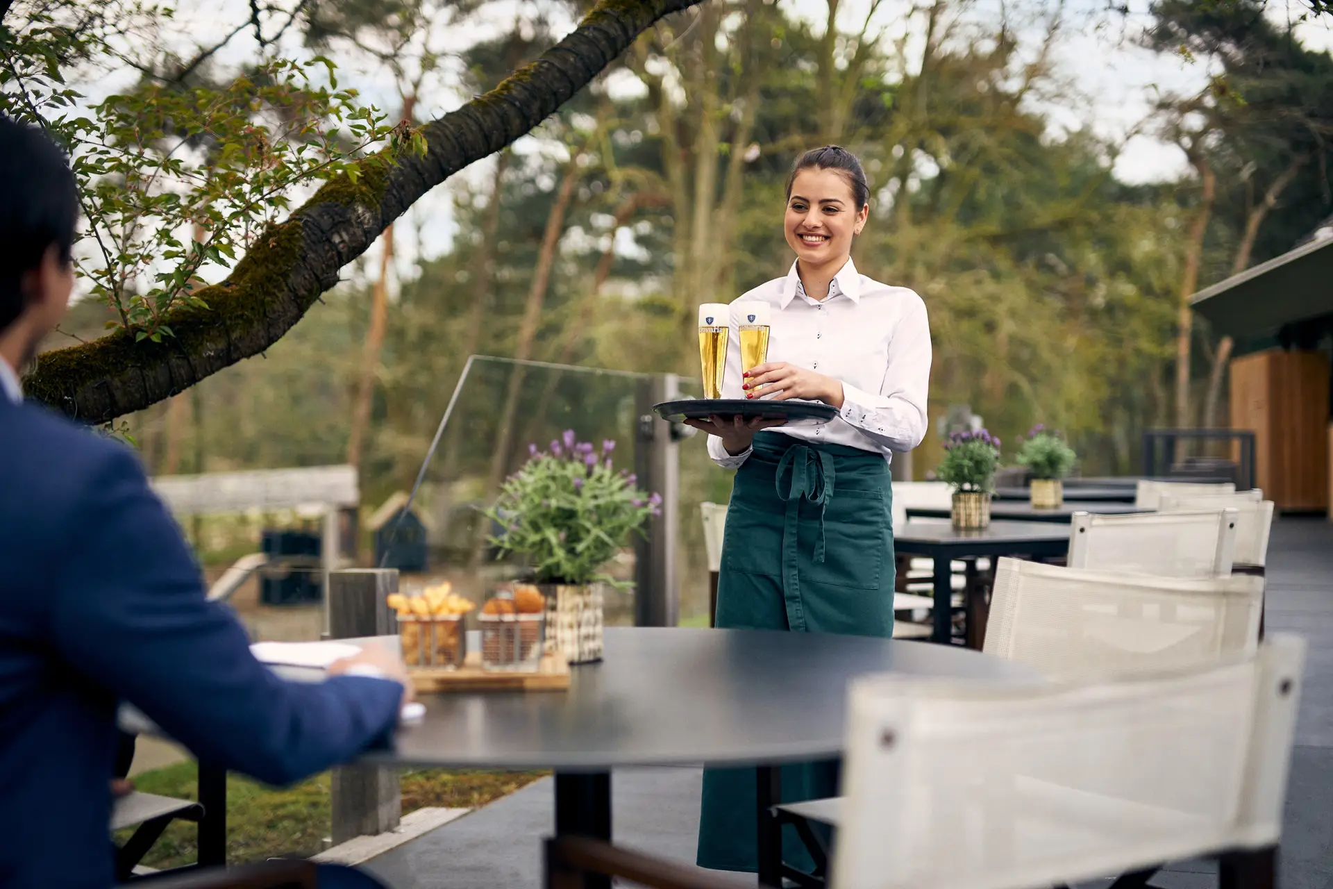 Vrouwelijke ober die buiten op het terras een drankje komt brengen